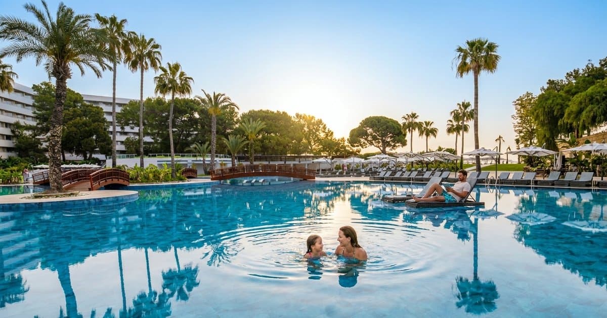 Утро у бассейна Rixos Premium Tekirova: мама с дочкой купаются среди пальм