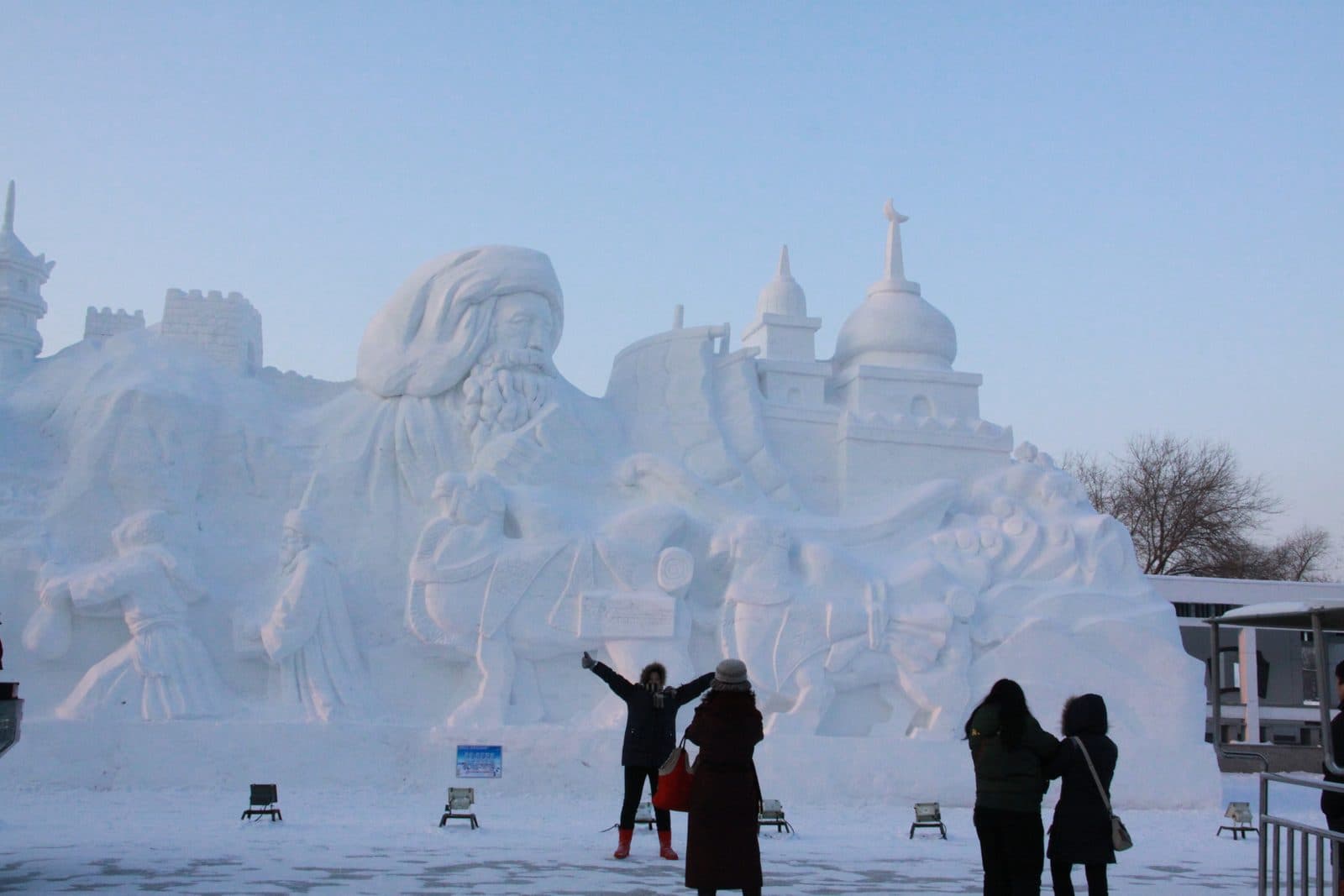 Огромная снежная скульптура на острове Солнца в Харбине, перед ней фотографируются люди в зимней одежде