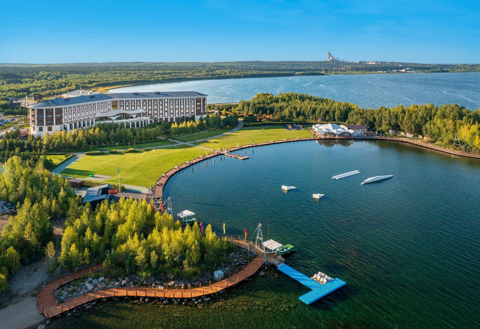 Отель Rixos Borovoe с высоты: длинный изогнутый корпус на берегу озера, зелёный газон, деревянная набережная с причалами, вокруг лес