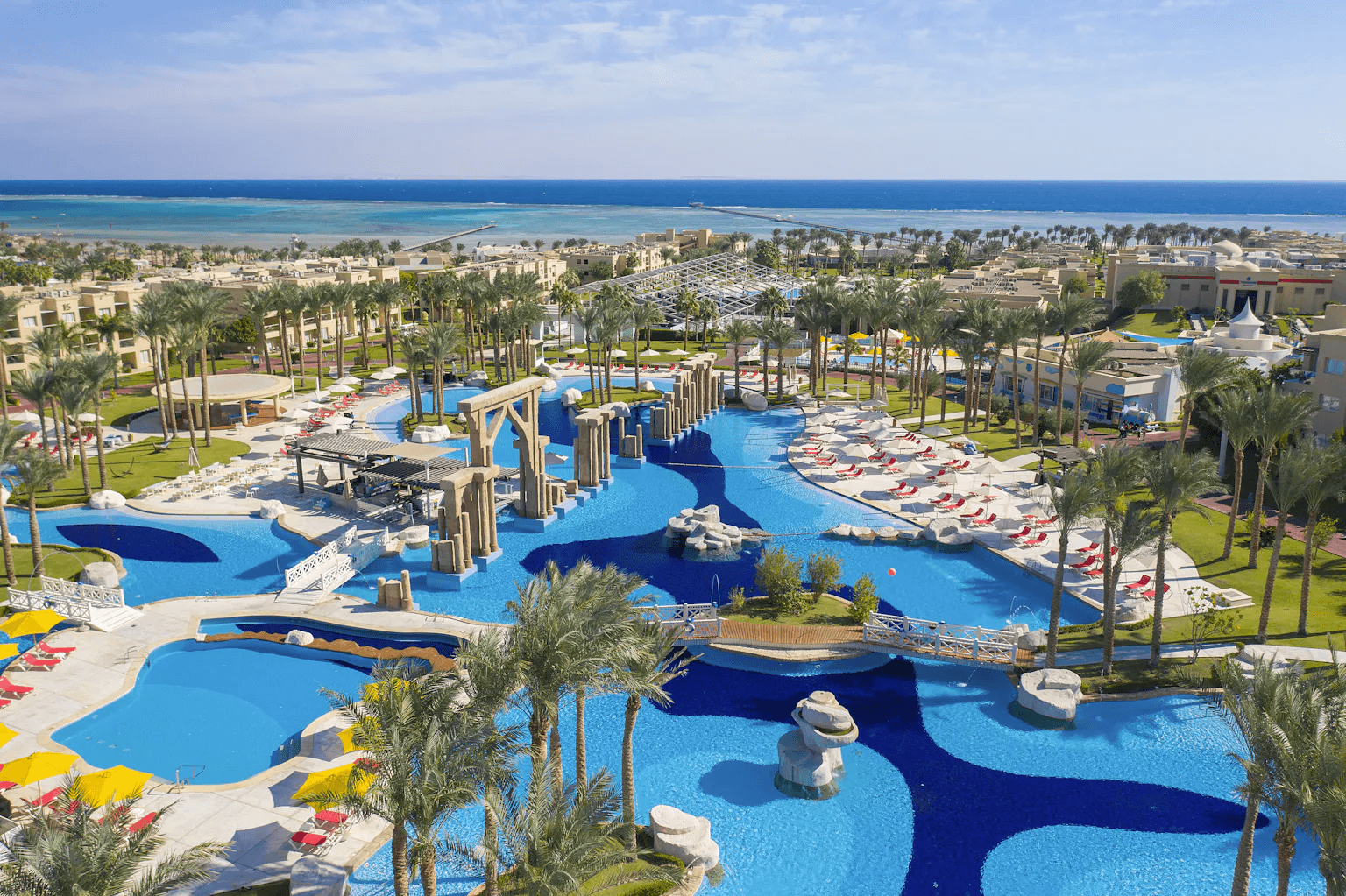 Rixos Premium Seagate сверху: бассейны-лагуны с мостиками и арками, пальмы, корпуса отеля и море на горизонте