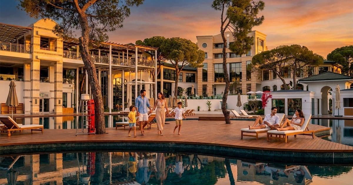 Закат у бассейна Rixos Park Belek: семья идет по деревянному настилу