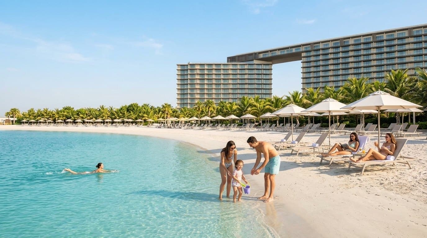 Солнечное утро на пляже Mövenpick Al Marjan: семья у кромки лагуны, позади две башни отеля
